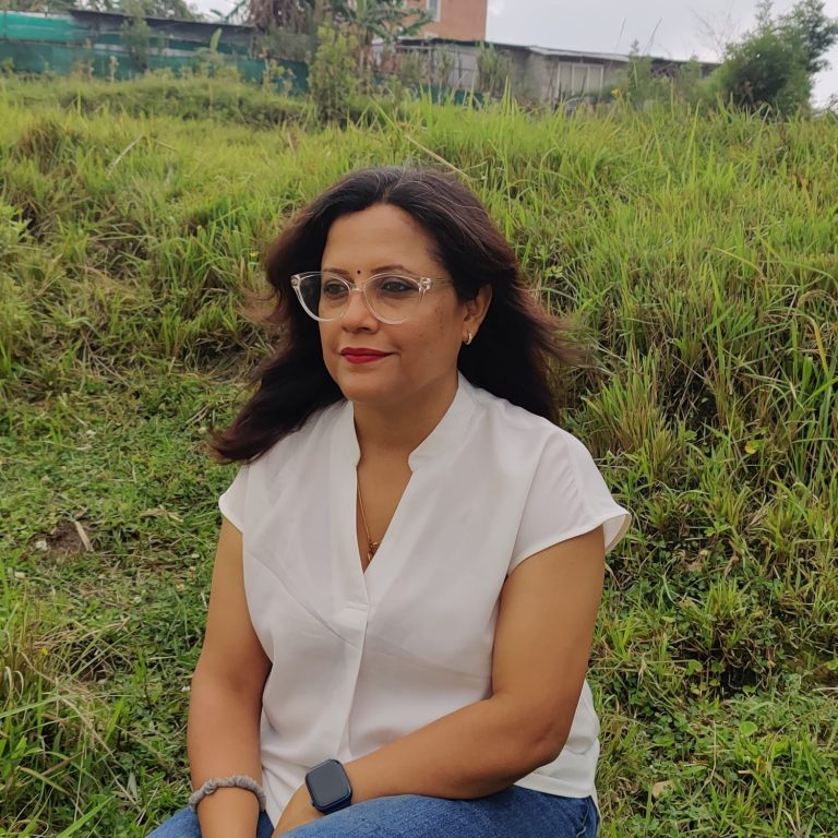 Pratiksha khanal sitting in a ground with greenery in back drop